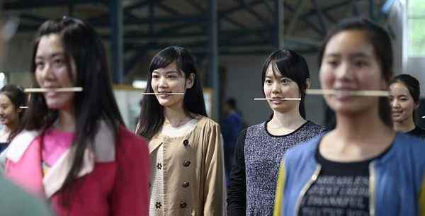 Китайские девушки отрабатывают улыбку, кусая палочки для еды