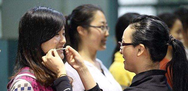 Китайские девушки отрабатывают улыбку, кусая палочки для еды Китайские девушки отрабатывают улыбку, кусая палочки для еды