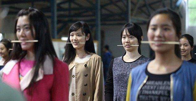 Китайские девушки отрабатывают улыбку, кусая палочки для еды Китайские девушки отрабатывают улыбку, кусая палочки для еды