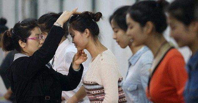 Китайские девушки отрабатывают улыбку, кусая палочки для еды Китайские девушки отрабатывают улыбку, кусая палочки для еды