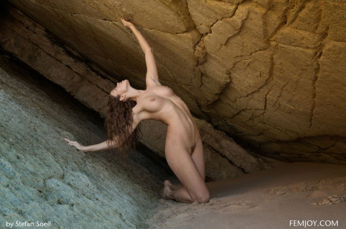 Голая девушка на пляже у скалы получает экстаз