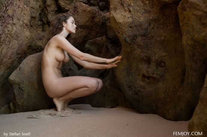 Голая девушка на пляже у скалы получает экстаз