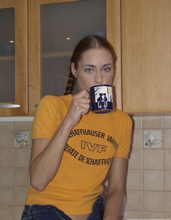 Женщина в джинсах раздевается на кухне