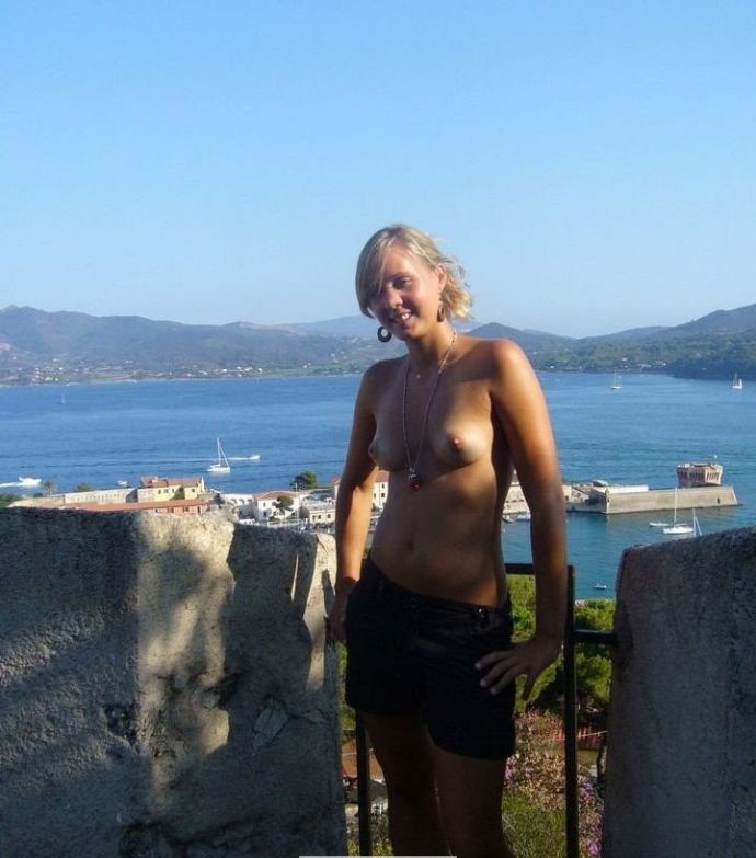 Прекрасная блондинка фотографируется топ-лесс на фоне голубого моря